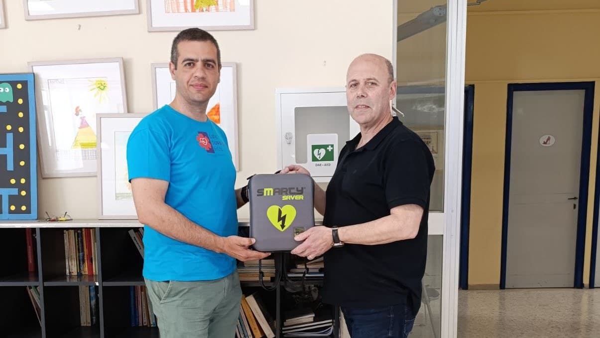 Παράδοση απινιδωτή στον διάδρομο του σχολείου· στον τοίχο διακρίνεται το επίτοιχο ερμάριο AED.